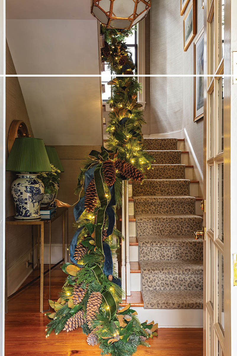 A mélange of greenery, lights, pinecones, and ribbons spills down the staircase.