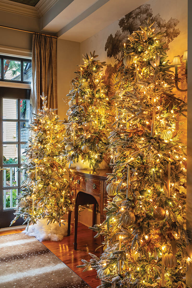 It’s all about layering: For the dining room’s winter wonderland, John adds dimension and volume to each tree and strand of garland through abundant candles, ornaments, and ribbon. But he also considers how complementary design elements—here, a collection of metallic tabletop trees, elegant potted paper-whites, and fluffy faux snow—will fully bring the space to life. After all, more is more during the holiday season.