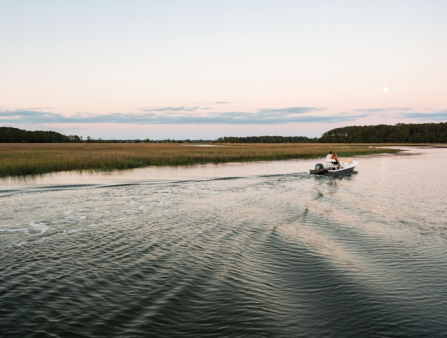 A boat cruises on Country Club Creek,