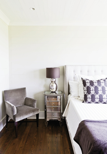 Luxe is More: The master bedroom is outfitted simply with an upholstered bed, mirrored nightstand, and a sable-toned velvet armchair.