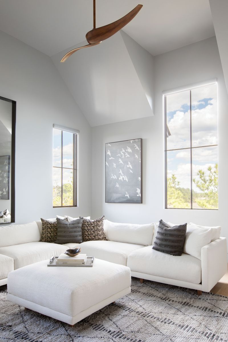 HANG TIME: With a big family of varying ages, having plenty of hang-out spaces was key. In the large, multipurpose den, a Robin Bruce “Neval” sectional and ottoman from Celadon provide ample room to stretch out and watch movies. The Sherwin Williams “Argos” paint adds a hint of blue to mimic the sky captured through the tall windows.