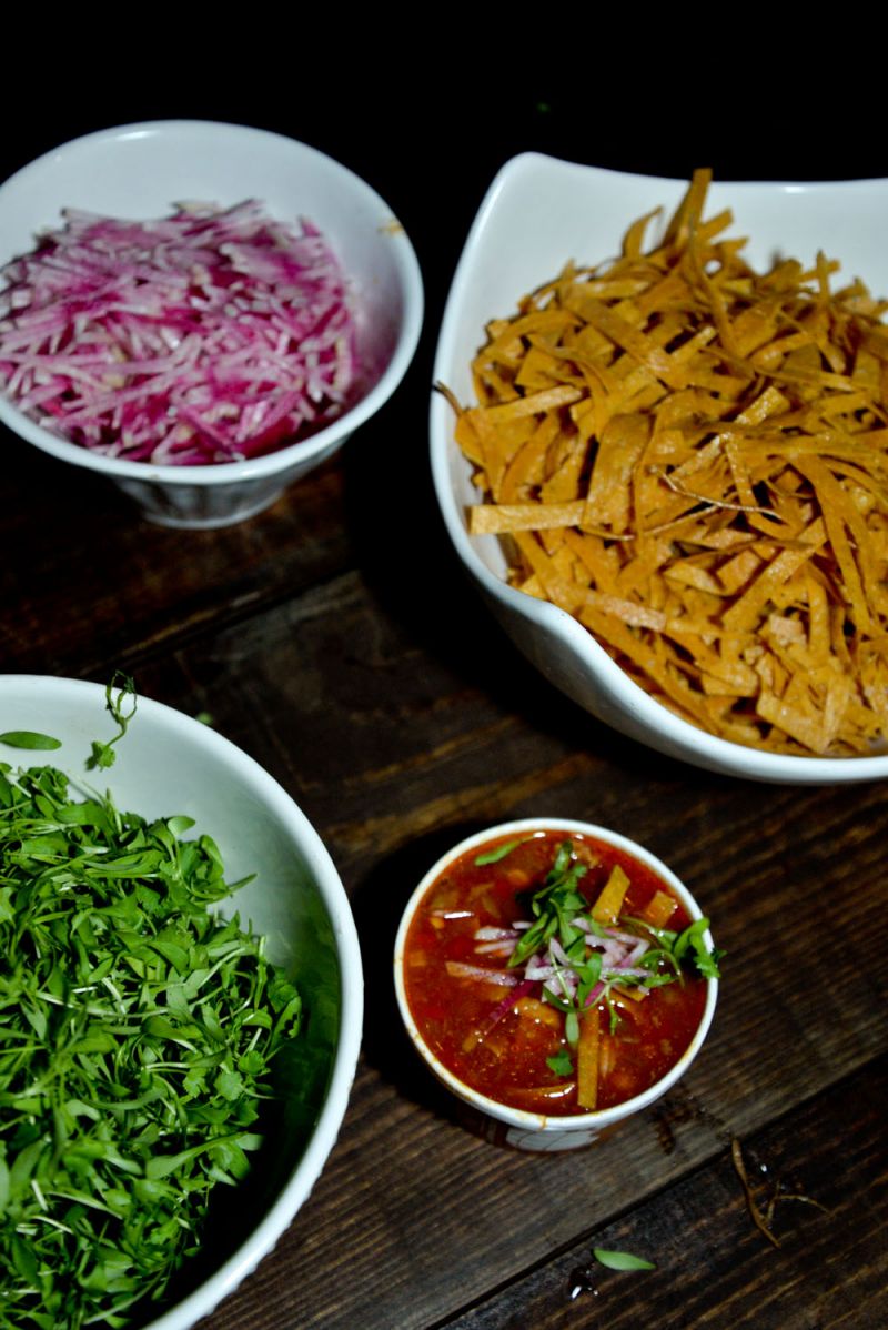Chili topped with micro cilantro, tortilla strips, and onions