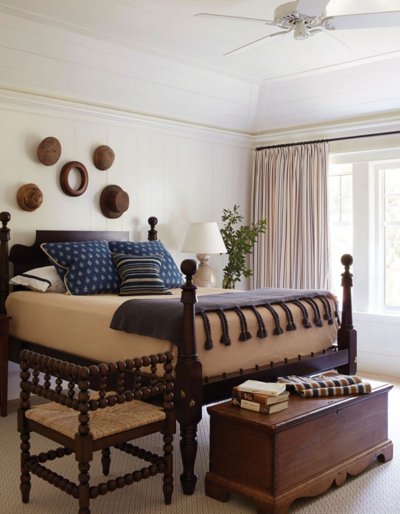 An antique bed and Mecox stool tie in with an antique trunk and hat moulds hanging on the wall to create handsome quarters.