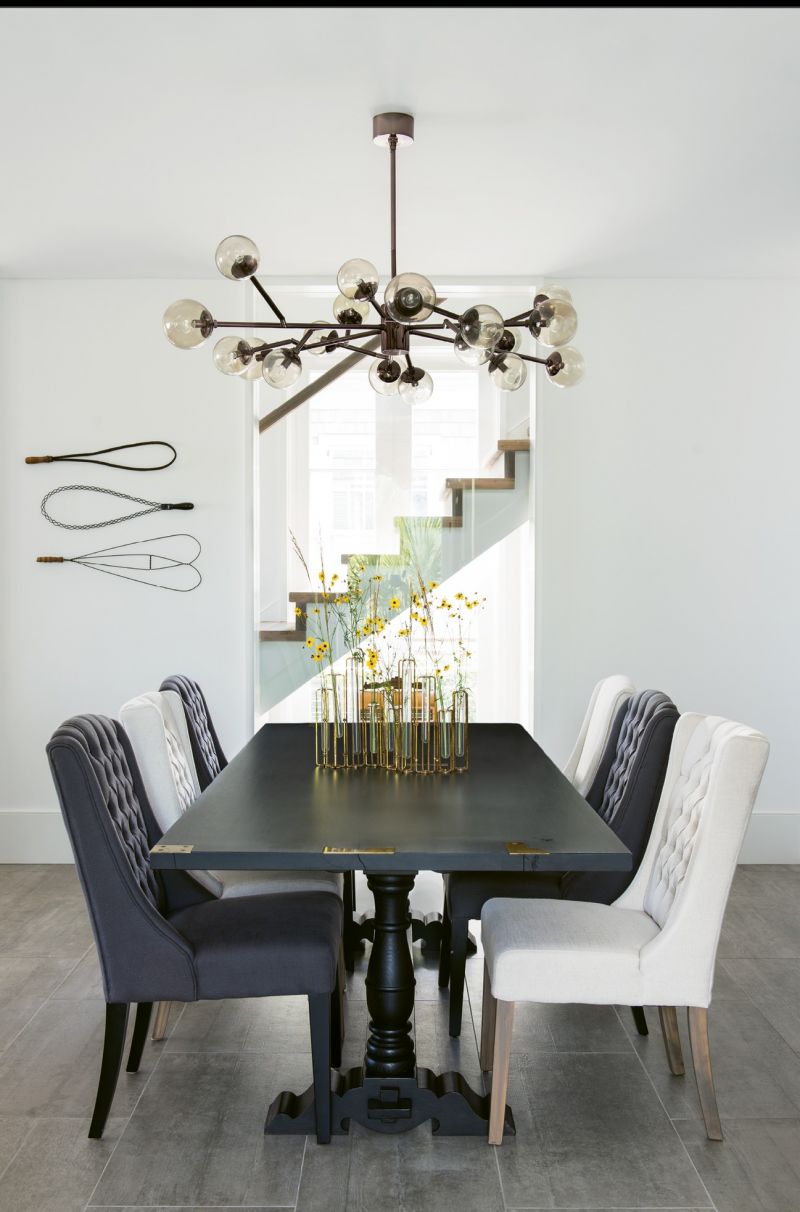 The couple commissioned cabinetmaker William C. Pritchard to produce a wooden table similar to one they had admired in the Hudson Valley. The upholstered chairs are from ABC Carpet &amp; Home, the mid-century-inspired “Dallas” chandelier from Arteriors.